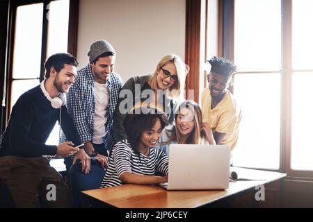 Going over the new assignment together. a group of university students working on an assignment together in class. Stock Photo