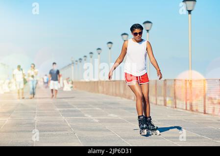 How I like to roll. an attractive young woman rollerblading on a boardwalk. Stock Photo