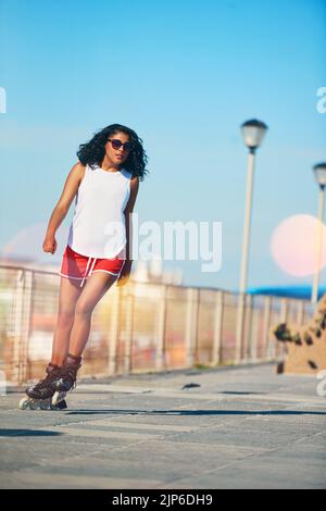 Why walk when you can skate. an attractive young woman rollerblading on a boardwalk. Stock Photo