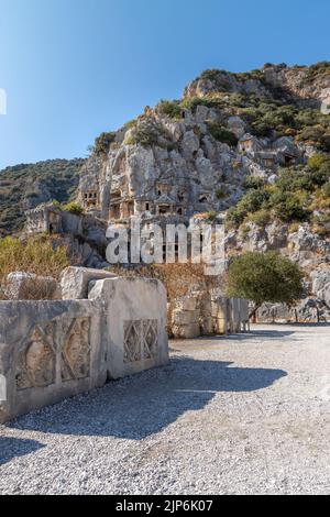 Vertical image of Historical Stone faces bas relief at Myra ancient city. Rock-cut tombs Ruins in Lycia region, Demre, Antalya, Turkey. Stock Photo