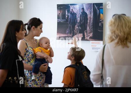 Kyiv, Ukraine. 14th Aug, 2022. People watch pictures by Azov soldier-photographer Dmytro 'Orest' Kozatsky shown at exhibition titled 'Unprecedented Azovstal' in Kyiv. Photographies by Dmytro 'Orest' Kozatsky show the realities of Azov regiment soldiers sieged at Azovstal steel plant in Mariupol. Before being captured Kozatsky published his pictures on social networks in order to spread them as widely as possible. (Photo by Oleksii Chumachenko/SOPA Images/Sipa USA) Credit: Sipa USA/Alamy Live News Stock Photo