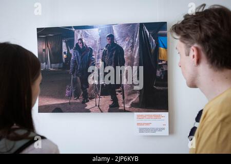 Kyiv, Ukraine. 14th Aug, 2022. People watch pictures by Azov soldier-photographer Dmytro 'Orest' Kozatsky shown at exhibition titled 'Unprecedented Azovstal' in Kyiv. Photographies by Dmytro 'Orest' Kozatsky show the realities of Azov regiment soldiers sieged at Azovstal steel plant in Mariupol. Before being captured Kozatsky published his pictures on social networks in order to spread them as widely as possible. (Photo by Oleksii Chumachenko/SOPA Images/Sipa USA) Credit: Sipa USA/Alamy Live News Stock Photo