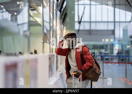 Frustrated sad young African man passenger having problems with check-in for flight Stock Photo