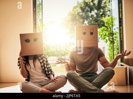 Bringing some fun into their new place. a couple wearing boxes with smiley faces drawn on them on their heads. Stock Photo