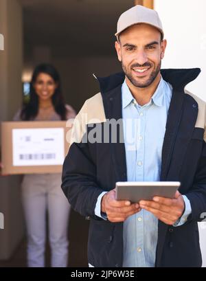 I manage everything on this little device. Portrait of a courier using a digital tablet while making a delivery to a customer. Stock Photo