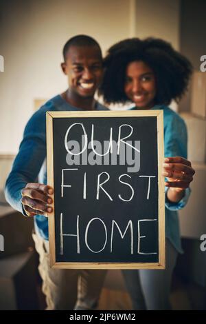 This is the new start weve been looking for. Portrait of a cheerful young couple holding up a sign saying our first home together while being Stock Photo