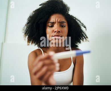 This cant be right... a young woman taking a pregnancy test at home. Stock Photo