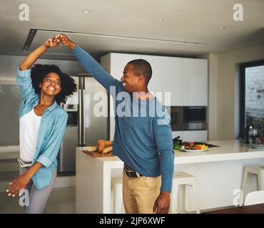 Spinning around. a cheerful young couple dancing together in the kitchen at home during the day. Stock Photo