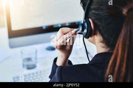 Managing the calls for the day. Rearview shot of a young woman working in a call centre. Stock Photo