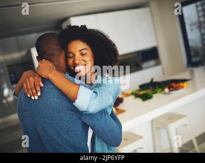 I want to stay like this forever. a cheerful young couple holding each other and sharing a tender moment in the kitchen at home during the day. Stock Photo