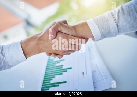 The deal has been finalized. Closeup shot of two businesspeople shaking hands over some paperwork in an office. Stock Photo