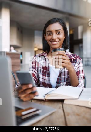 Using my break to catch up with friends. Cropped portrait of an attractive young female student using her cellphone while sitting outside on campus. Stock Photo