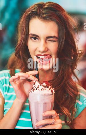 Mmmm now that was a yummy milkshake. a beautiful young woman drinking a milkshake in a diner. Stock Photo