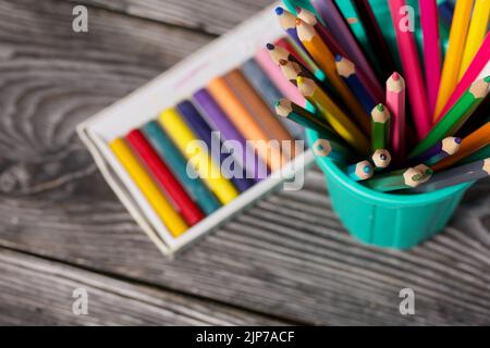 Colored pencils and pastels for drawing.  focus on pencils. On pine boards.  Top view Close-up. Stock Photo