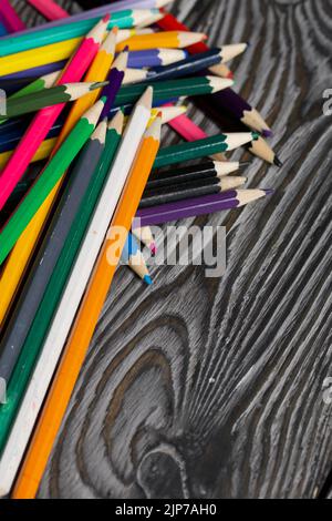 Colored pencils for drawing.  They lie on a table made of pine boards. Stock Photo