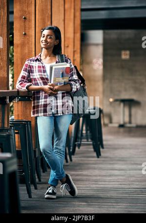 Enjoying being a student. a young female student holding textbooks outside on campus. Stock Photo