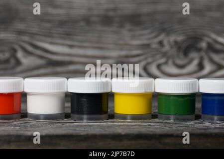 Gouache set.  Jars of paint are in a row.  On pine boards.  Close-up. Stock Photo