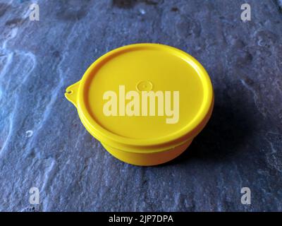 yellow plastic container box on stone background Stock Photo