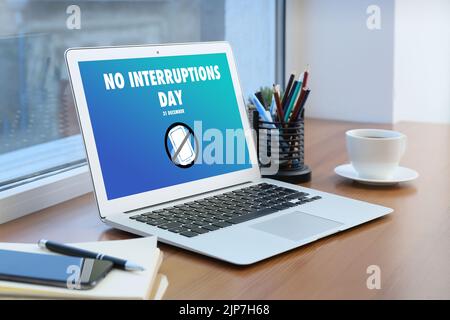 Text NO INTERRUPTIONS DAY on screen of computer monitor at workplace in ...