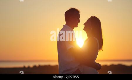 Couple stands showing pure love to each other at back sunset Stock Photo