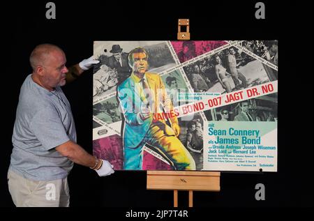 Previously unissued photo dated 02/08/22 of Propstore poster consultant Mark Hochman adjusting a German A0 poster for the 1962 James Bond film 'Dr No' (estimate £800 - 1,200) during a preview for their forthcoming poster auction at their auction house in Rickmansworth, Hertfordshire. Issue date: Tuesday August 16, 2022. Stock Photo