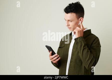 Young man wearing earbuds when calling his friend or colleague Stock Photo