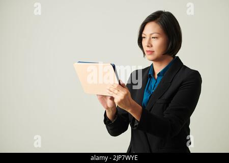 Portrait of female entrepreneur checking documents and emails on tablet screen Stock Photo
