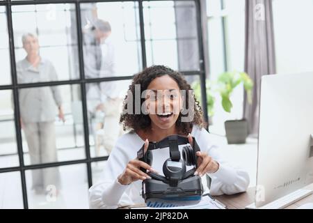 Girl in VR glasses of virtual reality with gamepad playing game Stock Photo
