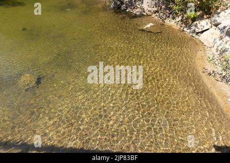 Water ripples texture on the shore of a natural pond against sand Stock Photo
