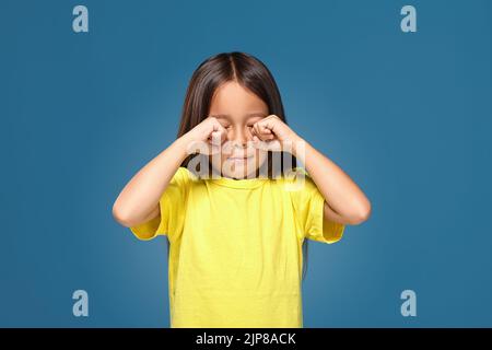 Sad offended little girl cries in yellow t-shirt Stock Photo