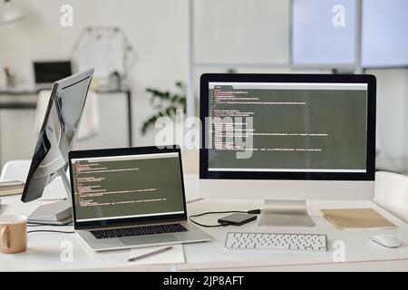 Close-up of computer monitors with codes standing on table at modern office Stock Photo