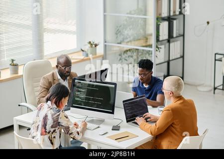 High angle view of Group of programmers working on computer and laptop with codes during teamwork at office Stock Photo