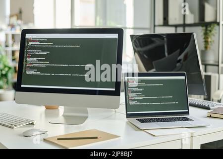 Horizontal image of computer with new software on screen with codes standing on table of programmer at office Stock Photo
