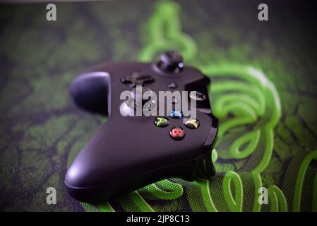 A close-up shot of a black xbox controller put on the green fabric Stock Photo