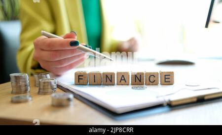 Woman pointing on word finance made of wooden cubes in row Stock Photo