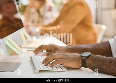Close-up of African programmer typing on keyboard at his workplace at office Stock Photo