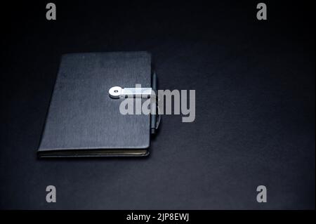 black planner or notebook with pen isolated on black background, mockup, copy space, close-up Stock Photo