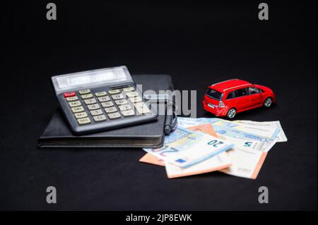 euro banknotes, calculator, notebook and red toy car on black background, loan and insurance concept Stock Photo