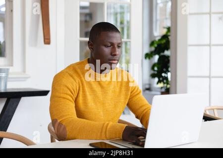 African american man using laptop at home and concentrating Stock Photo