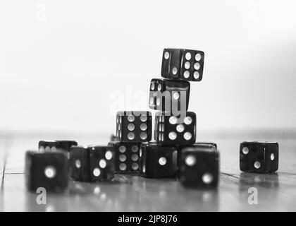 A black and white colored dice with different numbers stacked on a table Stock Photo