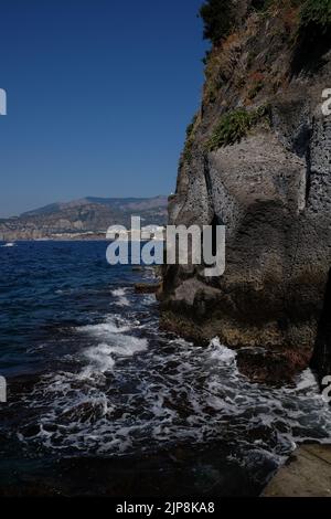 Close-up view of rock edge of Sorrento peninsular cliff  that meets the sea with a seagull nesting with the harbour and gulf of Naples in background Stock Photo