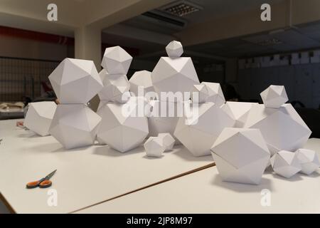 Geometric figures made of paper with a lot of surfaces are on the table. Stock Photo
