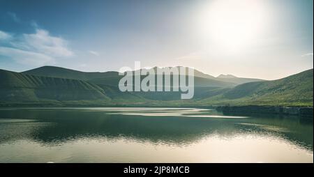 Sunrise landscape over lake and mountains with cloudy sky. Stock Photo