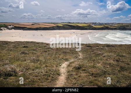 A rough footpathgn leading to a bench on Pentire Point East overlooking low tide at Crantock Beach on the coast at Newquay in Cornwall in the UK. Stock Photo