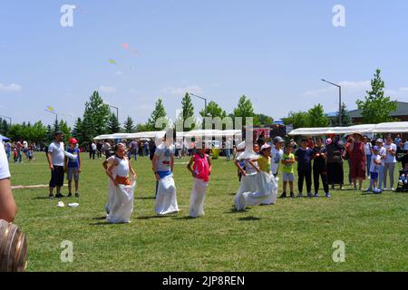 People and kids having fun at gunnysack race in summer outdoor Stock Photo