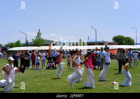 People and kids having fun at gunnysack race in summer outdoor Stock Photo