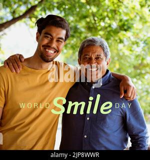 Composition of world smile day text over biracial man and his adult son embracing in garden Stock Photo