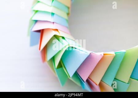 Fragment of an origami ring laying on a white background, abstract parametric structure made of colorful paper sheets, top view. Close up photo with s Stock Photo