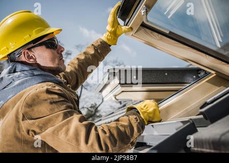 Close up of Caucasian Middle Aged Construction Worker Carefully Checking Fleshly Installed Roof Windows in Newly Built Residential House. Industrial T Stock Photo