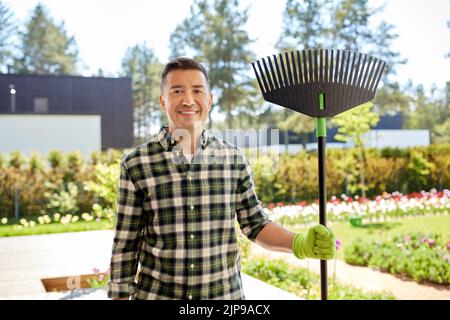 happy middle-aged man with leaf rake at garden Stock Photo